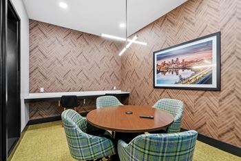 Conference room and wfh space with chairs, a table, tv, and charging ports